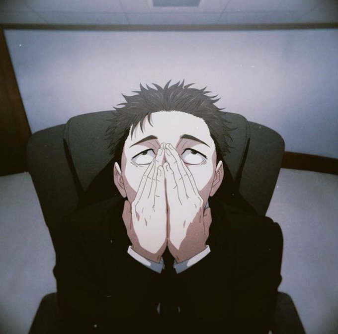 Anime character with dark spiky hair and dark eyes covers his face with both hands in an exasperated expression while sitting in a gray chair.