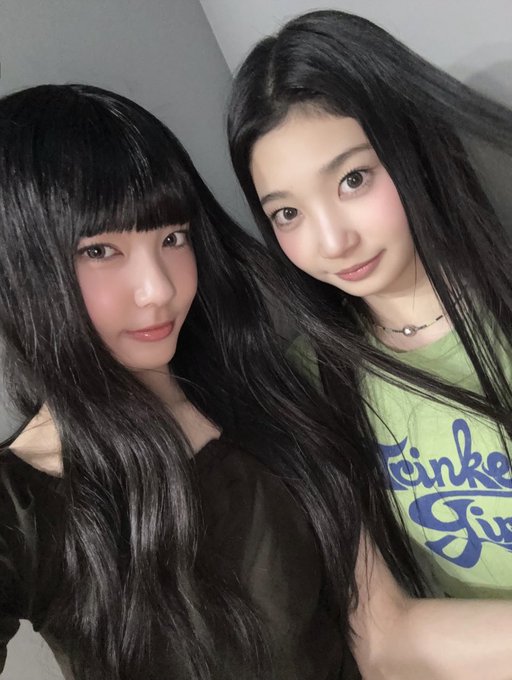 A selfie of two young women with long dark hair; one wearing a black top and the other wearing a green 'Twinkle' shirt.