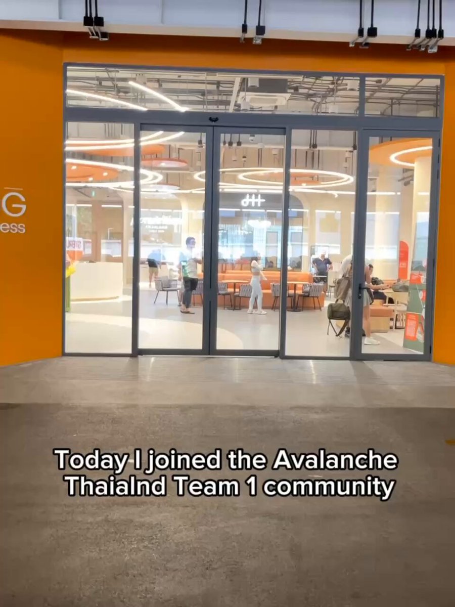 The image shows a group of people gathered inside an office building, possibly attending an event or meeting related to the Avalanche Thailand Team 1 Padel Event at Sterling Sport & Wellness. The team members are standing around each other, engaged in conversation and enjoying their time together. There is also a chair visible near one of the individuals.