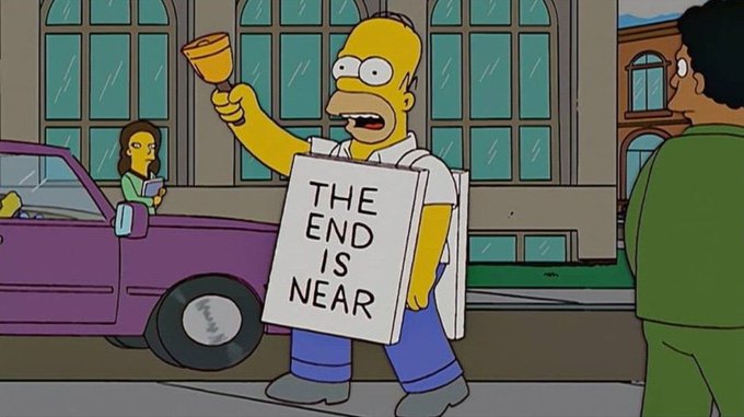 A scene from The Simpsons shows Homer Simpson holding a bell and a sandwich board sign reading 'THE END IS NEAR' on a rainy street corner.