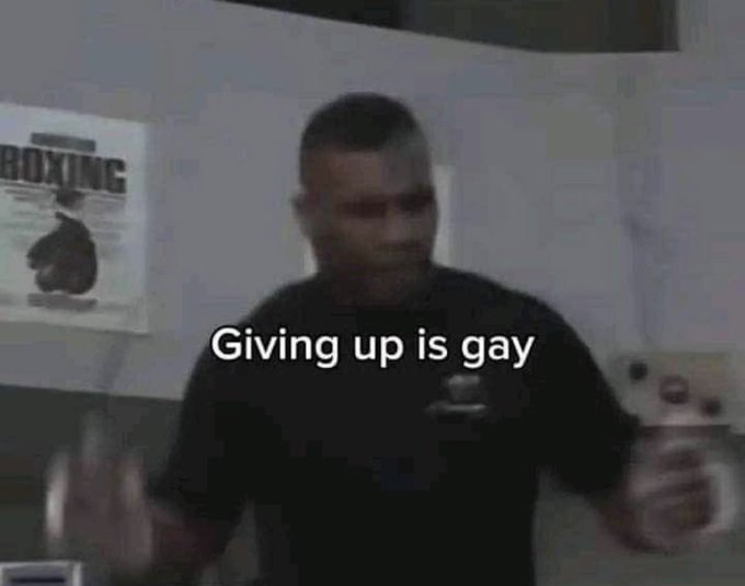 A low-resolution, grainy image shows a man in a black t-shirt standing in front of a 'BOXING' poster, with overlaid white text reading 'Giving up is gay'.