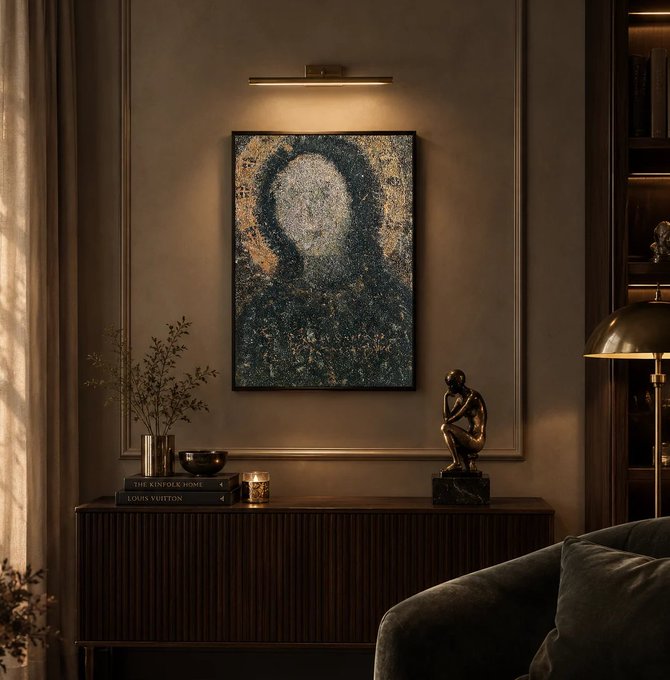 A moody, dimly lit interior scene featuring a framed impressionist-style portrait painting on a brown wall above a console table, with books including 'THE KINFOLK HOME' and 'LOUIS VUITTON', a bronze thinking figure sculpture, and a brass lamp.