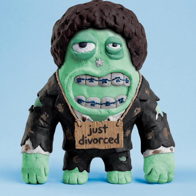 A claymation-style figurine of a green-skinned, zombie-like character in a tattered black suit with a cardboard sign around the neck reading 'just divorced'.