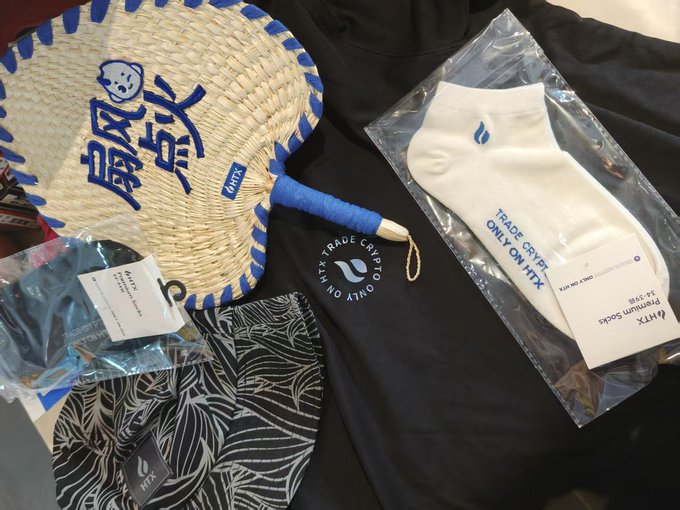 In this image, a variety of clothing items are displayed among other miscellaneous objects. A black t-shirt with Asian characters is prominently featured. To its right, there's a white sock featuring a blue light symbol, possibly representing a brand or product logo related to energy conservation. Another sock can be seen towards the top left corner of the image. The overall layout gives an impression that these items might be part of a clothing store display or a collection of unique clothing and accessories.