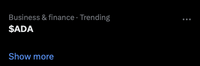 A dark mobile screenshot showing a 'Business & finance · Trending' section featuring the ticker '$ADA' with a 'Show more' link.