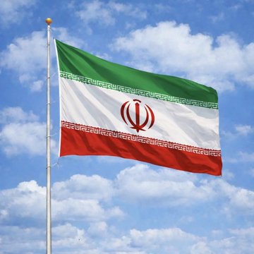 The Iranian national flag waves against a cloudy blue sky, displayed on a flagpole. The image accompanies news that the U.S. Senate has uncovered Iran's widespread use of Tether's $USDT stablecoin to circumvent sanctions, highlighting the regime's financial tactics under the symbolic colors of its banner.
