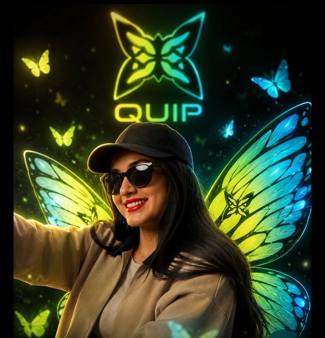 The image features a woman wearing sunglasses, a hat, and a tan jacket with her hair styled in loose waves. She has a big smile on her face as she poses for the camera. The background of the photo is dark, which contrasts nicely with the colorful butterfly wings that surround her. The butterflies are predominantly blue and green, adding to the overall visual appeal of the image.