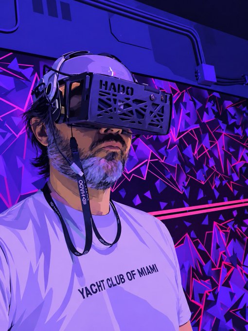 A stylized illustration depicts a bearded man wearing a HALO virtual reality headset and headphones, dressed in a white t-shirt that reads 'YACHT CLUB OF MIAMI', set against a purple and pink geometric background.