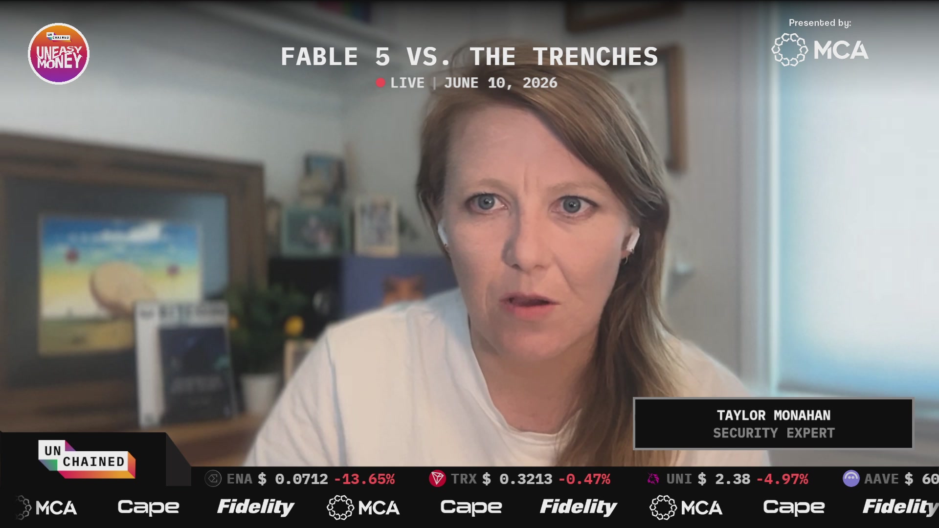 The image shows a woman sitting at a desk with a computer screen displaying a news broadcast about Fable 5 vs. The Trenches. She appears to be watching or participating in the broadcast, which could be an online event or a live stream. The image also includes text that reads "The most capable AI model ever launched this week, but it won't be auditing your smart contracts anytime soon".