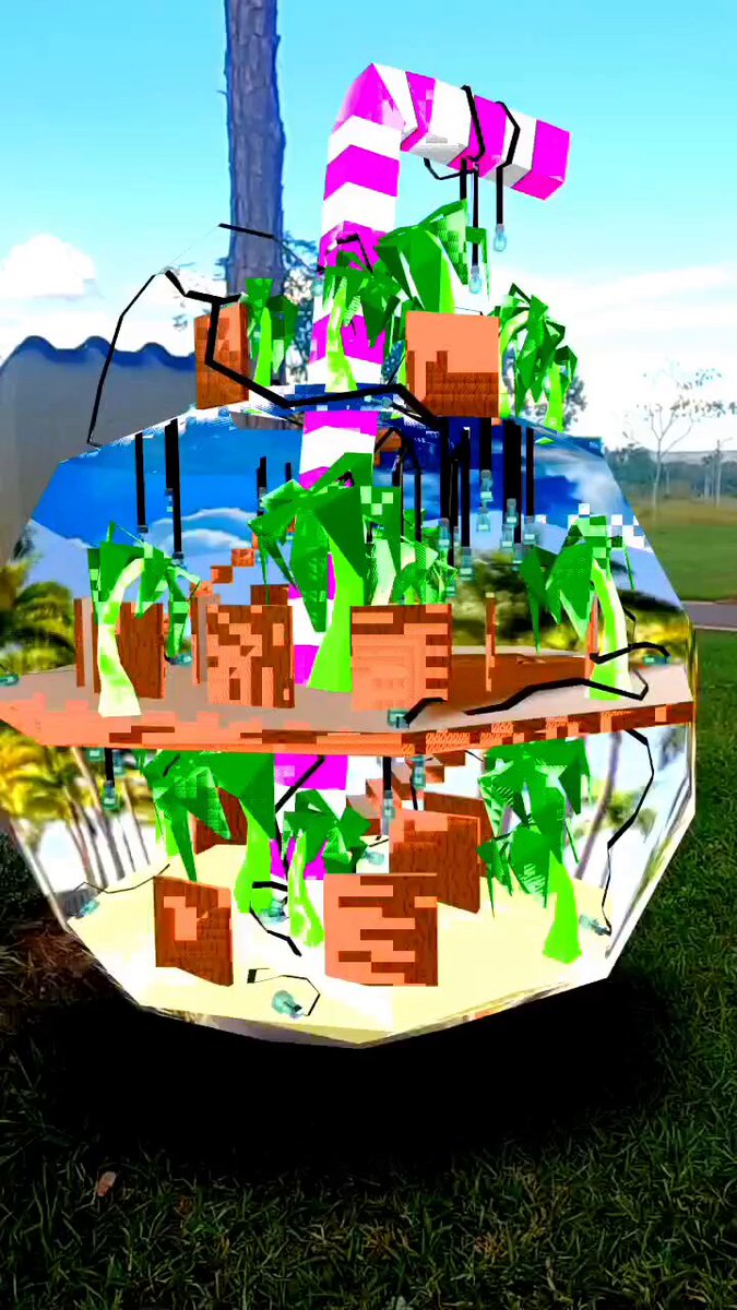The image features a 3D rendering of a candy cane, which appears to be made out of glass or plastic. The candy cane has a unique design that resembles a tree with branches and leaves, giving it an interesting and whimsical appearance. It is placed outdoors on a grassy area, likely in a park setting. The background includes trees and other natural elements, creating a pleasant atmosphere around the candy cane.