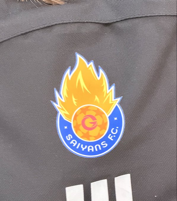 A close-up of a dark jersey featuring the Galatasaray S.K. logo with 'SAIYANS F.C.' text and a fiery yellow flame design.