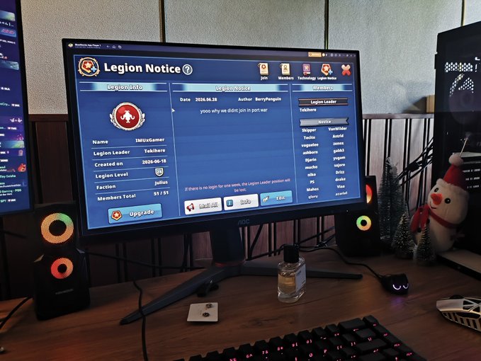 A gaming setup showing a monitor displaying a 'Legion Notice' page for 'LegionUnGamer' in the 'Julius' faction (created 2026-06-15, 51/35 members) by author 'Bennythegenis', flanked by RGB speakers, a Santa figurine, and a small Christmas tree.