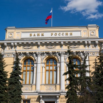 The neoclassical facade of the Bank of Russia, with its prominent "БАНК РОССИИ" signage and Russian flag flying above, reflects the central bank's regulatory role in the country's financial system, as referenced in the accompanying post about new crypto asset rules.