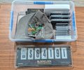 A plastic tackle/storage box with a clear lid containing small compartments and a digital scale labeled '8000000'.