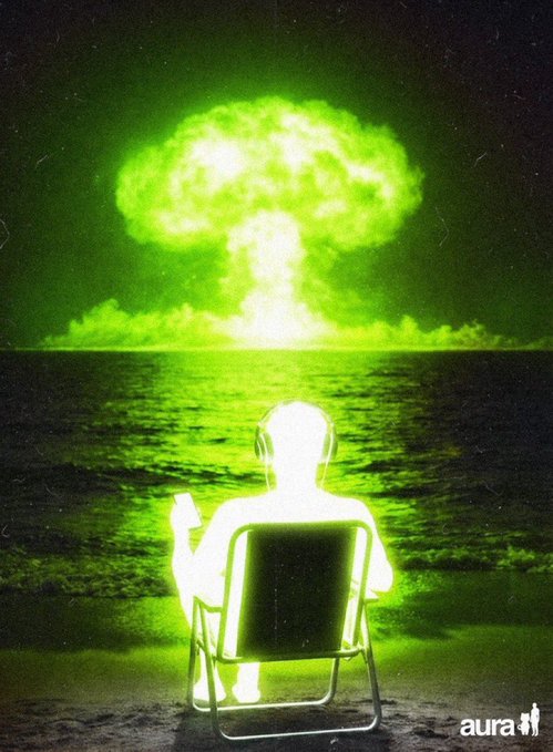 A glowing green figure sits in a beach chair facing a massive nuclear mushroom cloud rising over the ocean, with an 'aura' watermark in the corner.