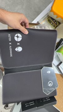 A hand holding two black boxes for a 'MASTER 4 MAXWELL' graphics card, appearing to be an unboxing of new computer hardware.
