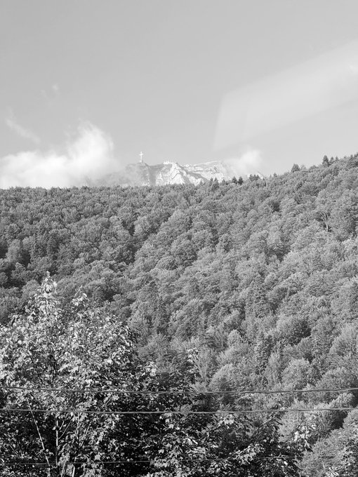 A black and white landscape photo showing a forested mountain with a cross visible at the peak, partially shrouded in clouds and mist.

The serene, expansive nature scene of mountains and forests contrasts with the post's mention of upcoming market volatility, suggesting a peaceful weekend before the trading week resumes.