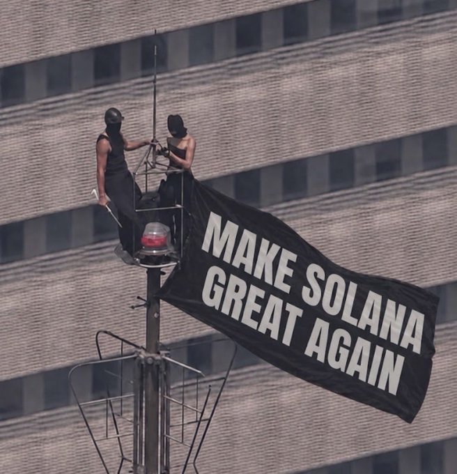 Two masked individuals atop a rooftop perch unfurl a banner reading "MAKE SOLANA GREAT AGAIN," mirroring the post's celebration of Solana's dominance in on-chain activity. The image playfully evokes political rally aesthetics to champion the network's leading role in crypto.