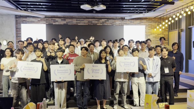 A group photo of competition winners at what appears to be an awards ceremony, with participants holding plaques labeled 'Technical Excellence,' 'Ecosystem & Innovation,' 'Grand Prize,' and 'Xcellence Award.'