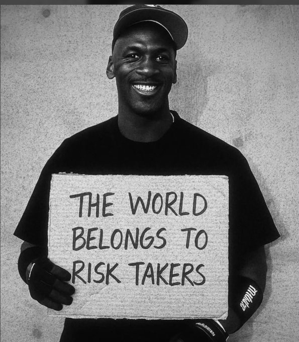 Black and white photo of Michael Jordan wearing a cap and a t-shirt with handwritten text reading 'THE WORLD BELONGS TO RISK TAKERS'.