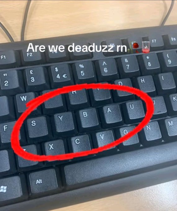 A close-up of a black keyboard shows missing caps circled in red, with the text 'Are we deaduzz rn 🪦🥃' overlaid.