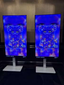 Two digital kiosk or display screens showing identical blue-toned artwork, labeled "BABY XATS" and "BFT" at the bottom.