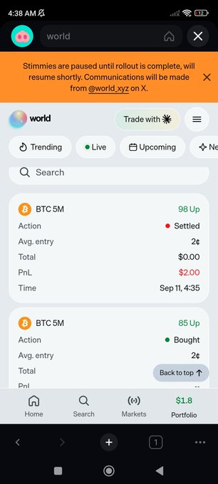 A mobile screenshot of the 'world' app showing a paused status message at the top, with portfolio entries for BTC 5M, including one settled action showing a $2.00 PnL and another bought entry.