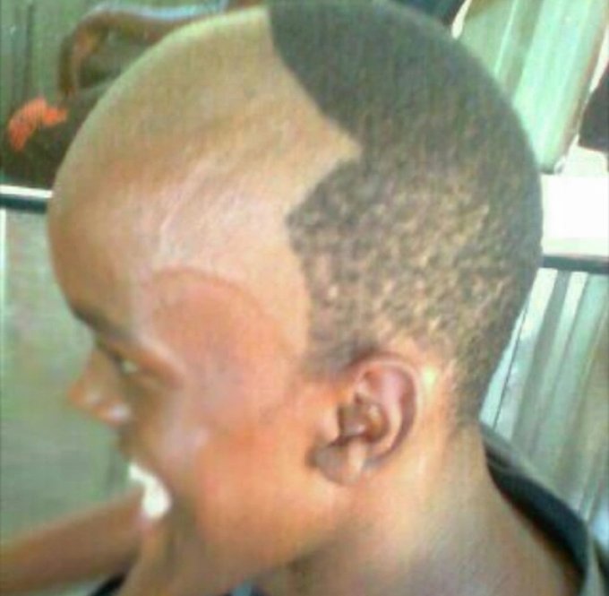 A close-up side profile of a person with a unique haircut that features shaved patterns and textured designs on the back and sides of their head.