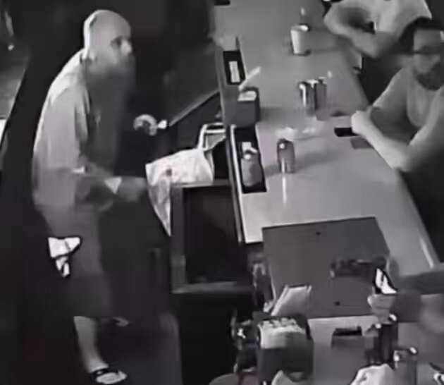 The image shows a man wearing a grey shirt standing at a dining table with other people present, suggesting that they are gathered for a meal or some social event. The photo appears to be taken indoors, possibly within a restaurant or bar setting. There is also an interesting element in this photo - the presence of multiple beverage cans and bottles scattered across the table, along with cups on another side. Additionally, there is a cell phone and a computer mouse placed close together, indicating that some technology might have been used to capture the scene. The post appears to discuss the history of farming and how it was once considered a thing, which could possibly be related to agriculture or daily life during that period in an earlier time frame.
