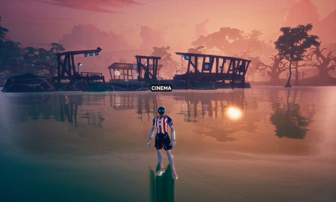 A video game character stands in shallow water facing a settlement labeled 'CINEMA' across a sunset-lit lagoon with floating docks.