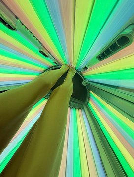 A person's arms reach upward from below in a room filled with radiating, multicolored light beams, with a car visible in the background. The dynamic perspective and "it's time." caption suggest a moment of anticipation or arrival, as if the subject is stepping into an immersive, otherworldly experience at the threshold of something significant.