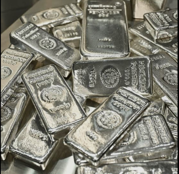A pile of silver bars stamped with 'Heraeus' and 'Feinsilber 999.0' is shown.