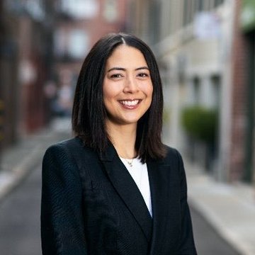 The image shows a smiling woman with shoulder-length dark hair, wearing a black blazer, standing in what appears to be an urban street setting. The photo likely depicts Monica Long, Ripple's President, as referenced in the post about the upcoming XRP Seoul event scheduled for October 3, 2026, at the Grand Hyatt Seoul during Korea Blockchain Week.
