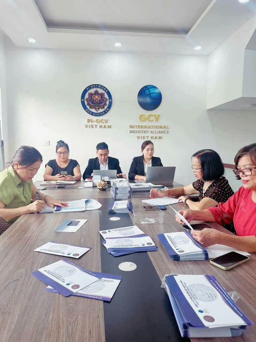 A group of people sit around a conference table in an office displaying "PI-GCV VIET NAM" and "GCV INTERNATIONAL INDUSTRY ALLIANCE VIET NAM" logos on the wall, reviewing stacks of documents and certificates. The post highlights Pi Network's strong performance in Vietnam with the PiGCV valuation of 314.159$ and 7 billion Pi, though the scene of members gathered signing certificates reinforces the skeptical comment comparing it to a multi-level marketing scheme.
