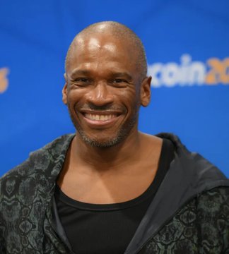 A smiling Arthur Hayes, co-founder of BitMEX and CEO of Flop Labs, appears at a conference, as referenced in the post announcing his release of the FLOP Network v0.5.0 draft white paper, with a partial "coin" logo visible on the backdrop behind him.