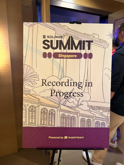 A sign at the entrance of the Solana Summit Singapore event reads "Recording in Progress," indicating an active session is underway at the conference powered by Superteam. A person is partially visible to the right of the display, aligning with the post about the start of the event tour in Singapore.