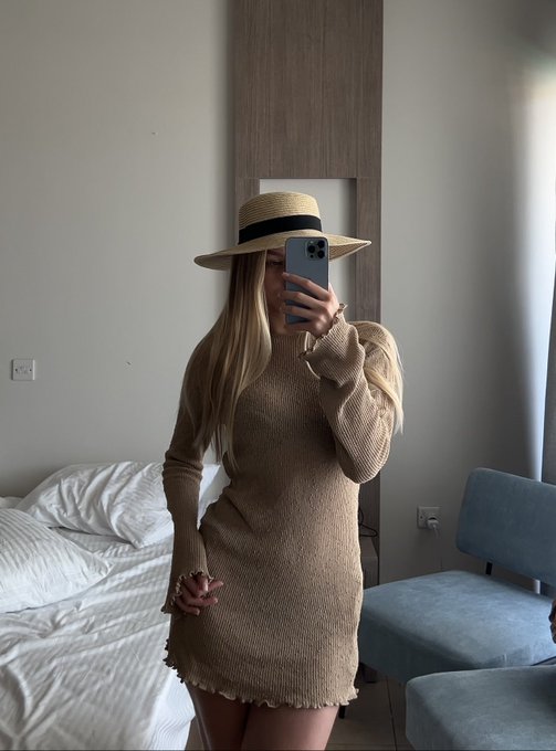 A mirror selfie shows a person in a beige sweater dress and straw hat holding a smartphone in a minimalist bedroom. The image serves as a confident, lifestyle-forward visual to accompany a post celebrating a successful 24-hour run of NFT mints, altcoin trades, and launchpad gains.
