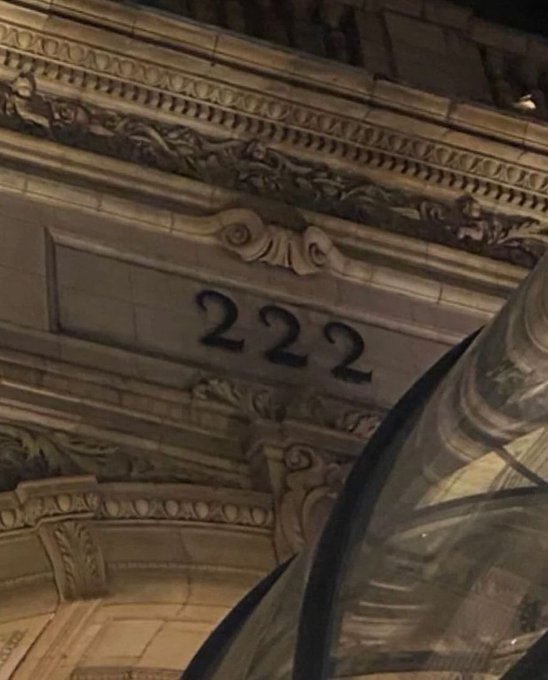 vernacular architectural style building with ornate carvings and a large number "222" on the front, set against a dark night sky.