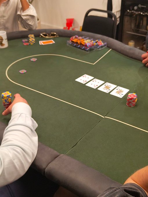 A view of a poker table with green felt, showing community cards, player chip stacks, and players' hands visible around the table.