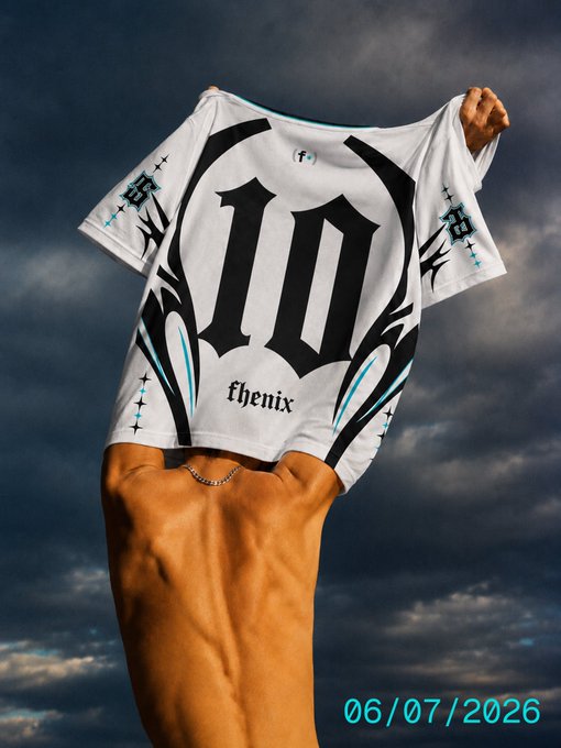 A person's hands hold up a white t-shirt displaying "10" in large black Gothic lettering and "fhenix" below, alongside "f" and "fh" logos and cross motifs, against a stormy sky. The "06/07/2026" date stamps the image, directly tying to the post's announcement of the Fhenix swag shop drop on that date.
