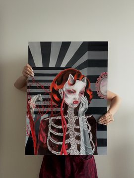A child holding up a large vertical art print featuring an illustration of a figure with skull face makeup, red horned headpiece, and skeleton-patterned clothing against a radiating background.