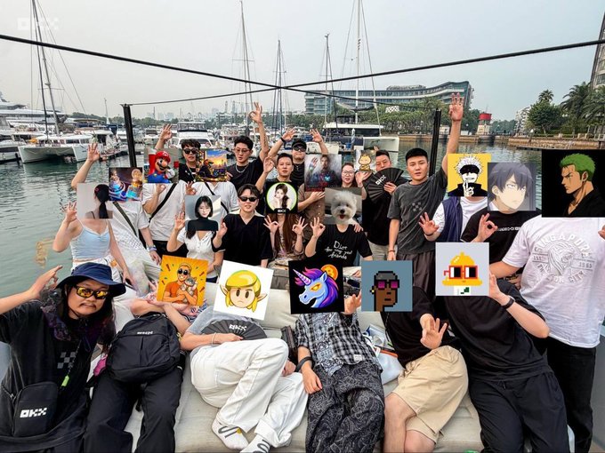 A group of people posing together on a dock, with several anime-style avatar overlays obscuring their faces, and boats visible in the background harbor.