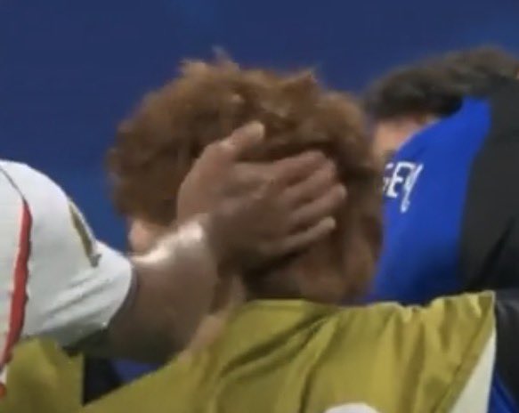 A young soccer player in a yellow goalkeeper jersey covering their face with their hand, appearing emotional during a match.