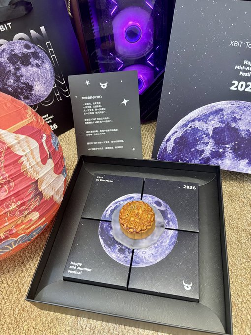 An opened merchandise box from 'XBIT' featuring a 2026 Happy Mid-Autumn Festival mooncake designed with a moon graphic, alongside a greeting card and product packaging.