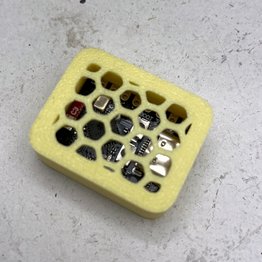 The image shows a yellow plastic container with a hexagonal pattern, likely used for storing electronic components or other small items. The container has a black screen inside of it, which could be an electronic device or component. The background appears to be white, providing contrast and making the colors of the container stand out.