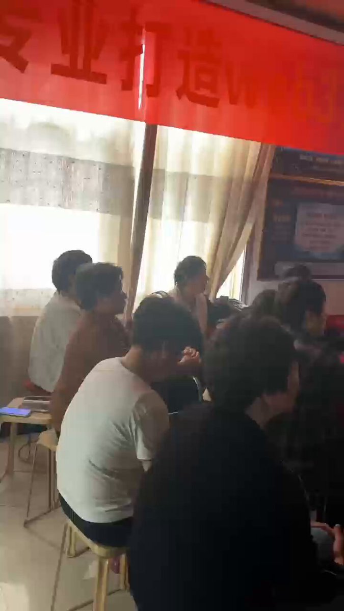 The image shows a group of people sitting around a table with chairs, engaged in conversation or working together. They are facing away from the camera, which suggests that they might be discussing something related to the post about crypto MLM schemes. The caption provided seems to be unrelated to the scene and does not provide any context for what is being discussed by the group of people.