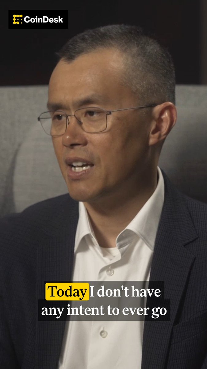 A man in a dark blazer and glasses speaks during an interview, with the CoinDesk logo in the top left corner and a partial caption reading "Today I don't have any intent to ever go" displayed at the bottom. The image relates to the accompanying post about CZ (Changpeng Zhao) of Binance stating he has no plans to return as CEO.