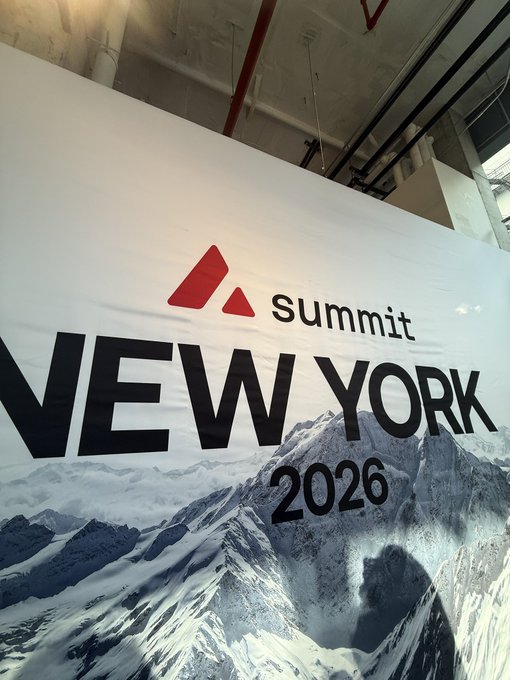 A banner displays the red logo 'summit' above the text 'NEW YORK 2026' with a snowy mountain graphic, hanging in a large room.