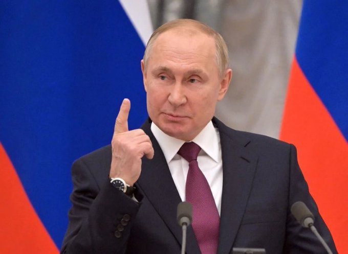 Russian President Vladimir Putin gestures while speaking in front of the Russian flag, aligning with the news that Russia's Central Bank may legalize Bitcoin and crypto for international trade.