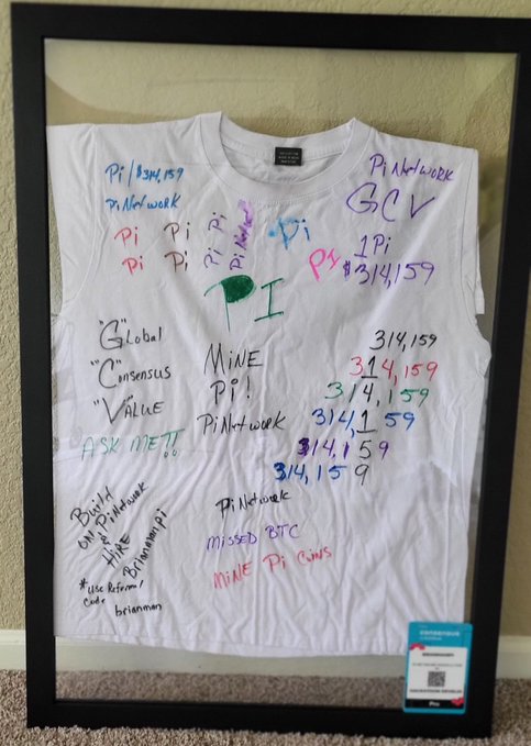 A framed white t-shirt signed by the global Pi Network community is displayed, covered in messages like "Pi Network," "Pi 3/14/159," "MINE Pi!," "Global Consensus Value," and "GCV," along with references to BTC and "Pi Cons." The post expresses gratitude toward non-USA Pioneers for their participation and support, highlighting disappointment that US-based Pioneers have not engaged despite claiming to want involvement in the Pi Network project.